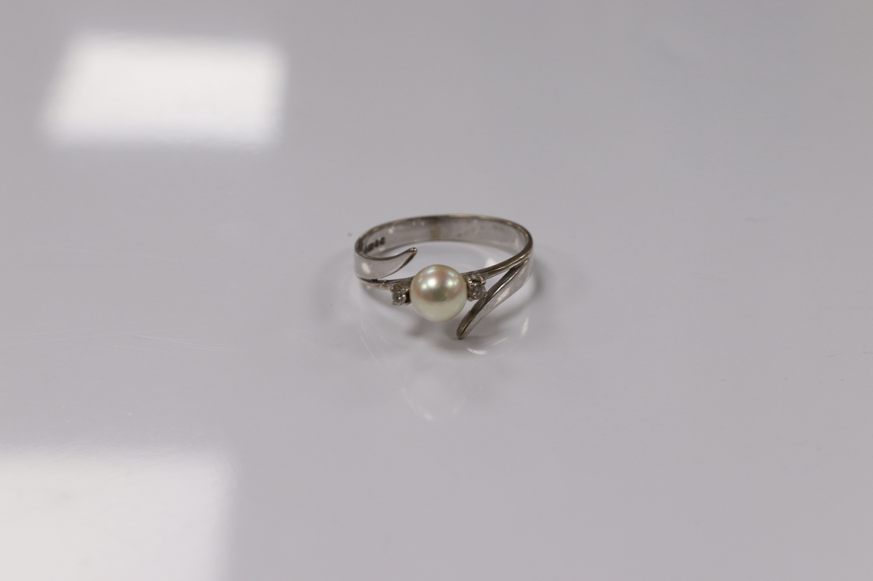 A modern 18ct white gold and single stone cultured pearl set ring, with two stone diamond set shoulders, size Q, gross weight 3.7 grams. Condition - poor to fair